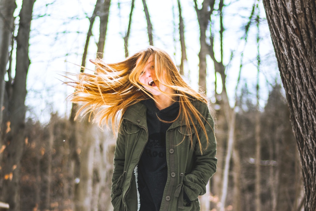 Woman walking in woods in winter - being out in natural light is important for managing Seasonal Affective Disorder (SAD)