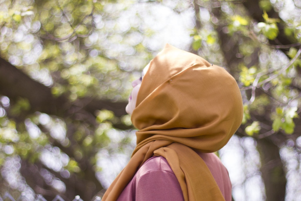 lady wearing a hijab taking an outdoor walk tilting her face up to the sunshine